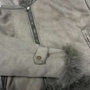 Detail of a faux suede jacket with plush fur trim and metal zipper closure