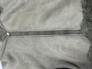 Detailed close-up of a silver metal zipper on a grey faux suede motorcycle jacket