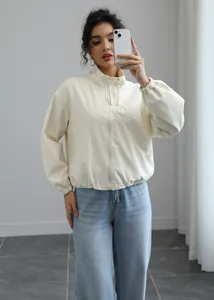 Close-up view of a cream waterproof windbreaker featuring a stand collar and front zipper