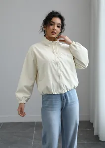 Woman wearing a stylish cream waterproof windbreaker with a modern short stand-collar design