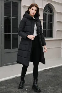 Full-length view of a woman in a slim black long hooded winter puffer coat