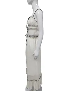 Side view of white two-piece set featuring a pleated camisole and ruffled long skirt