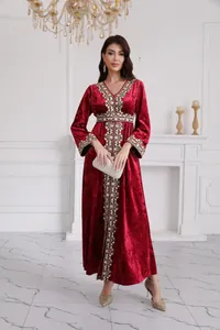 Detailed view of red velvet maxi dress featuring intricate golden embroidery and V-neckline
