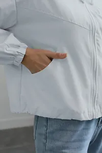 Close-up of the functional side pocket on a white waterproof windbreaker jacket for women.
