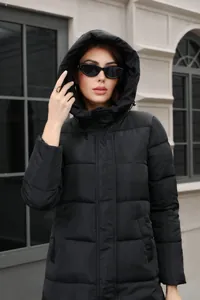 Detailed outdoor view of women's black hooded long puffer jacket with slim fit quilted design