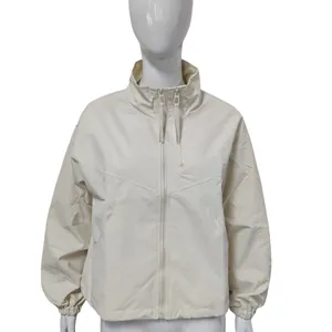 Detailed view of women's short cream windbreaker with stand collar and zipper pocket