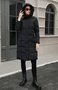 Full body view of a woman wearing a black long hooded puffer coat in street setting