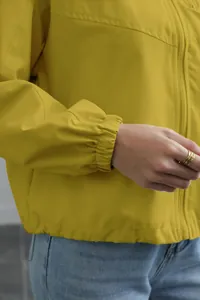 Close-up detail of yellow waterproof windbreaker jacket showing elastic cuff and zipper