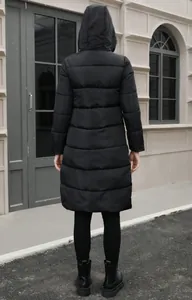 Detailed back view of a long black hooded puffer jacket for women during winter