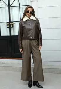 Modelo con chaqueta de cuero marrón vintage con cuello de borreguillo y pantalones anchos