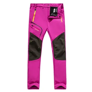 Pantalones impermeables de senderismo magenta con rodillas reforzadas negras.