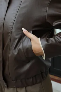 Detalle de chaqueta de cuero sintético marrón con forro de lana de cordero en el puño.