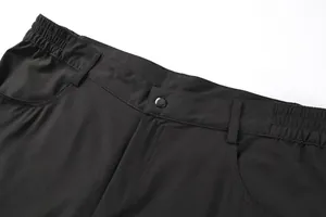 Close-up of men's black outdoor shorts waistband with snap button and elastic side.