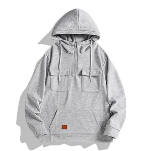 Vista frontal de sudadera gris con capucha, cremallera media y bolsillos de pecho