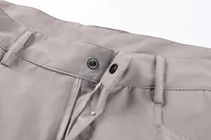 Close-up view of functional snap button and zipper fly on men's grey cargo shorts