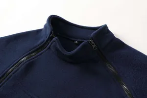 Dettaglio del colletto rialzato e della doppia cerniera di una giacca in pile blu scuro maschile