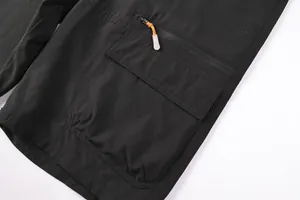 Close-up of black outdoor cargo shorts with functional zipper pocket and orange toggle