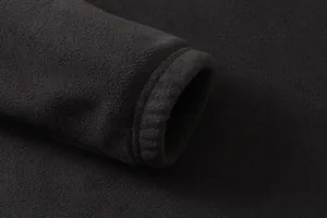 Dettaglio del morbido tessuto in pile e del polsino elastico su una felpa nera da uomo.