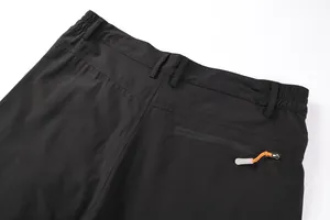 Close-up of black men's outdoor shorts featuring a zipper back pocket with orange puller.