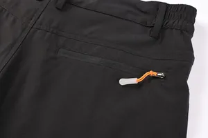 Close-up of black cargo shorts with zippered pocket and orange pull cord detail