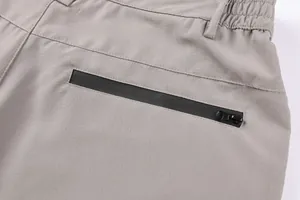 Close-up detail of a black waterproof zipper pocket on grey tactical cargo shorts for men