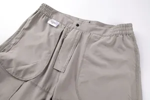 Detailed view of men's khaki functional cargo shorts waist showing metal button and care label