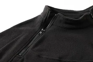 Dettaglio ravvicinato di un pullover tattico in pile nero con mezza zip per uomo
