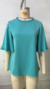 Detail view of teal blouse featuring a ruffled round neckline and bell sleeves
