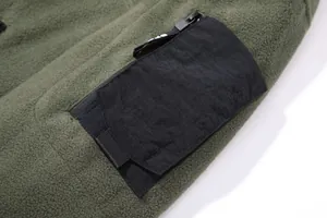 Detailansicht der schwarzen Reißverschlusstasche am olivgrünen Fleece-Taktik-Hoodie