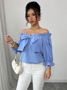Gros plan de la blouse bleue à épaules dénudées avec un grand nœud et des volants.