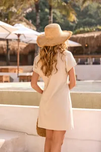 Back view of a beige waffle-knit short sleeve dress styled with a straw hat at a beach resort.