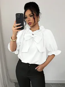 Gros plan d'une blouse blanche à épaules dénudées avec un grand nœud et volants