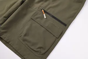 Detail view of army green outdoor cargo shorts showing pocket with zipper pull
