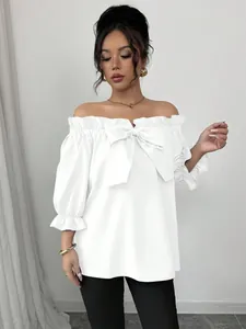 Élégante blouse blanche à épaules dénudées avec un grand nœud et des détails volantés.