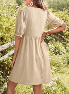 Detailed back view of a beige puff sleeve dress with tie cuffs in a garden setting