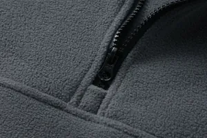 Primo piano della texture del pile grigio e dettaglio della cerniera di qualità.