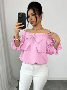 Gros plan sur une blouse rose à épaules dénudées avec un grand nœud et des volants
