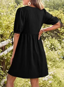 Detailed back view of a black bubble sleeve mini dress with tie details in a garden.