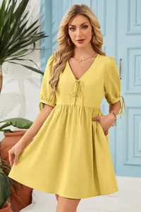 Close-up of yellow V-neck puff sleeve dress with tie-front detail and side pockets