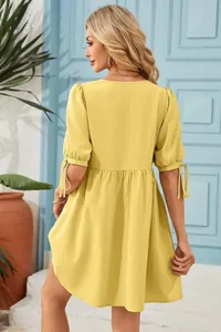Back view detail of yellow loose dress featuring puff sleeves with delicate tie closures.