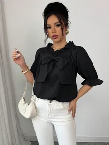 Élégant chemisier noir pour femme avec un grand nœud et des volants autour de l'encolure.