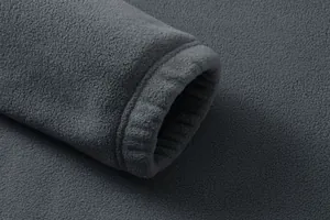 Dettaglio macro del morbido polsino elasticizzato di una felpa in pile grigio scuro