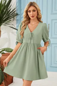 Detail view of a sage green V-neck dress with tie-up puff sleeves and a high waist.