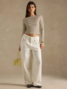 Model wearing a brown and white striped boat neck long-sleeved T-shirt in a studio setting.