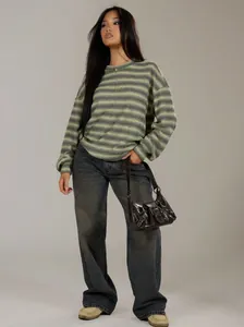 Full body model shot of a striped oversized sweatshirt with wide-leg dark jeans.