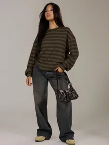 Full body view of a woman in an oversized striped crewneck sweater and wide-leg jeans