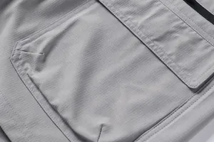 Close-up detail of grey ripstop fabric and pocket stitching on men's outdoor shorts.