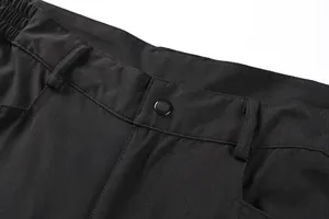 Detail view of men's cargo pants waistband featuring black button and durable ripstop fabric