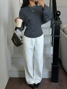 Detailed view of fashionable striped batwing sleeve t-shirt paired with white trousers