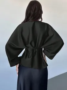 Back view of elegant black satin batwing sleeve blouse with tie-back detail.